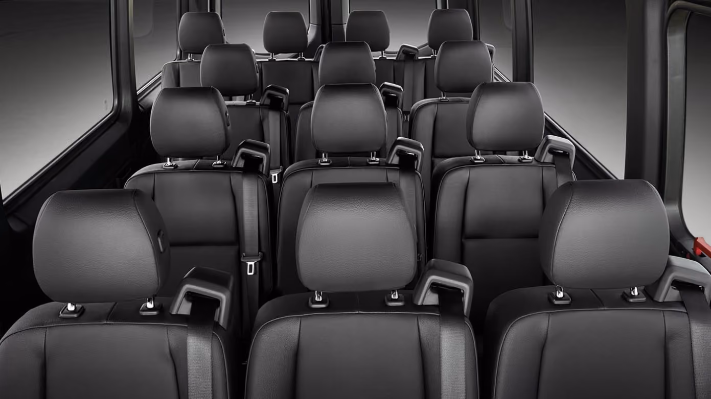 Rows of black leather passenger seats inside a van on a dark background