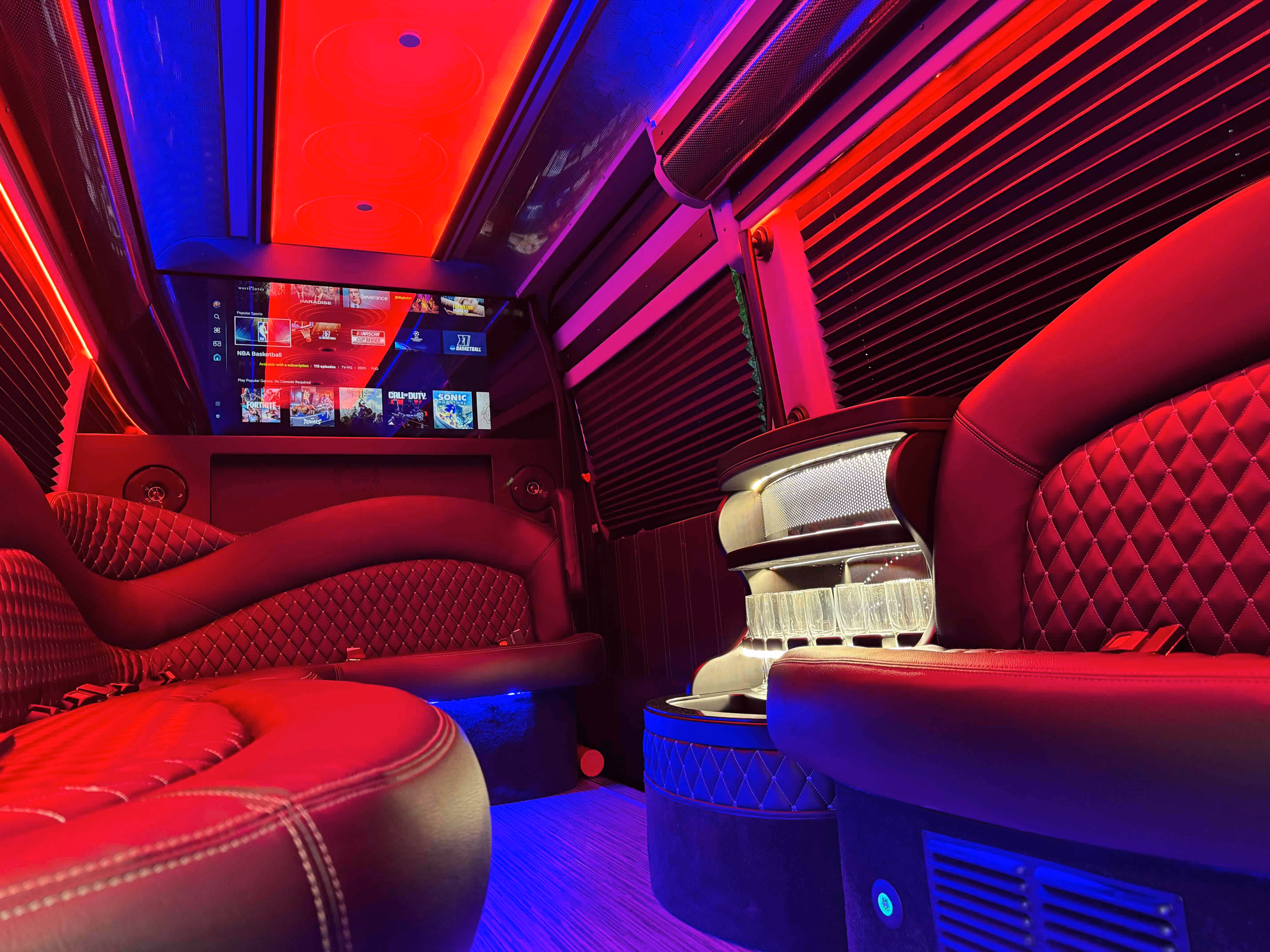 Limo van interior with red leather bench seating and red and blue LED lighting