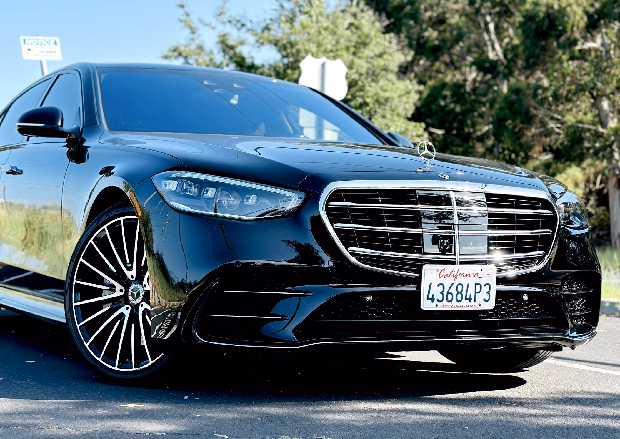 Black Mercedes sedan parked on a tree lined street in daylight