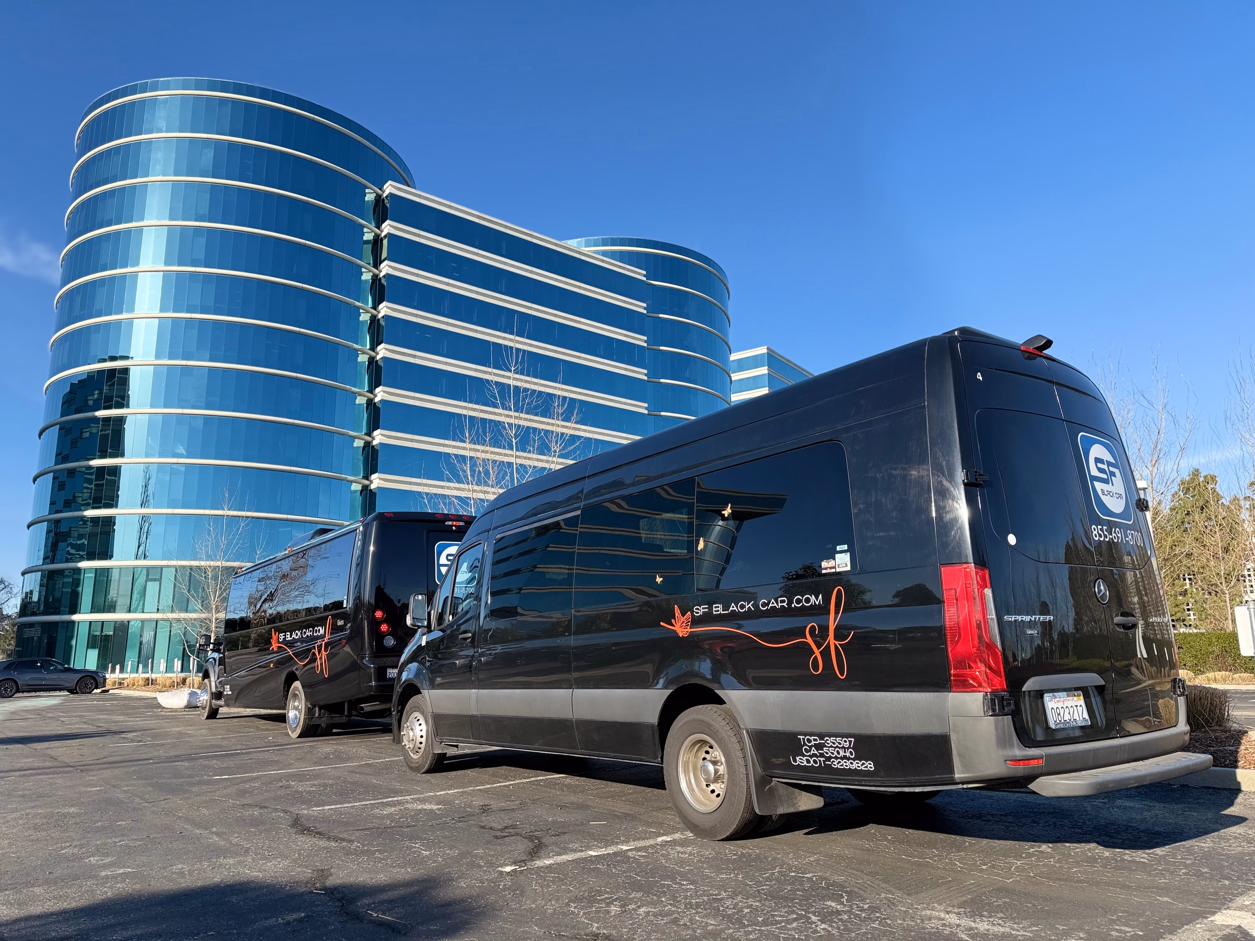 Black SF Black Car Sprinter van parked outside a curved glass office building