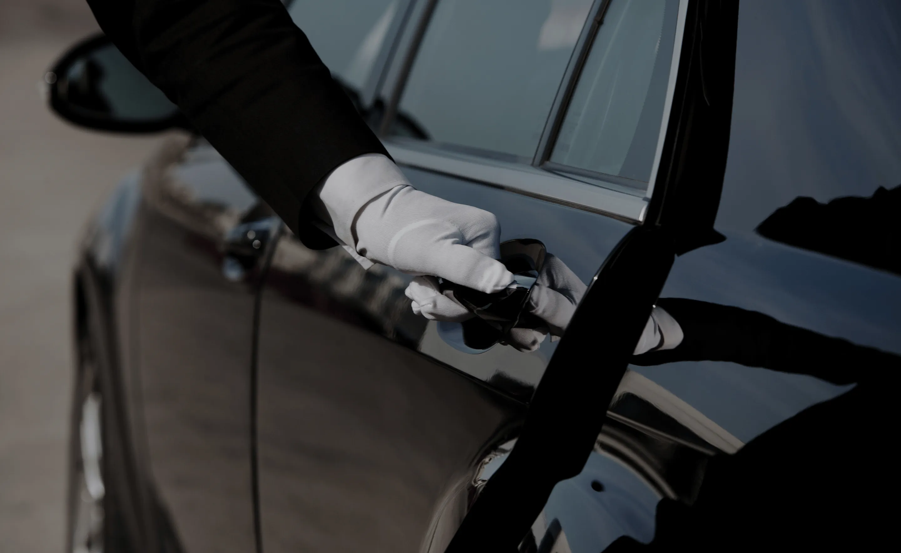 Chauffeur öffnet Tür einer schwarzen Limousine