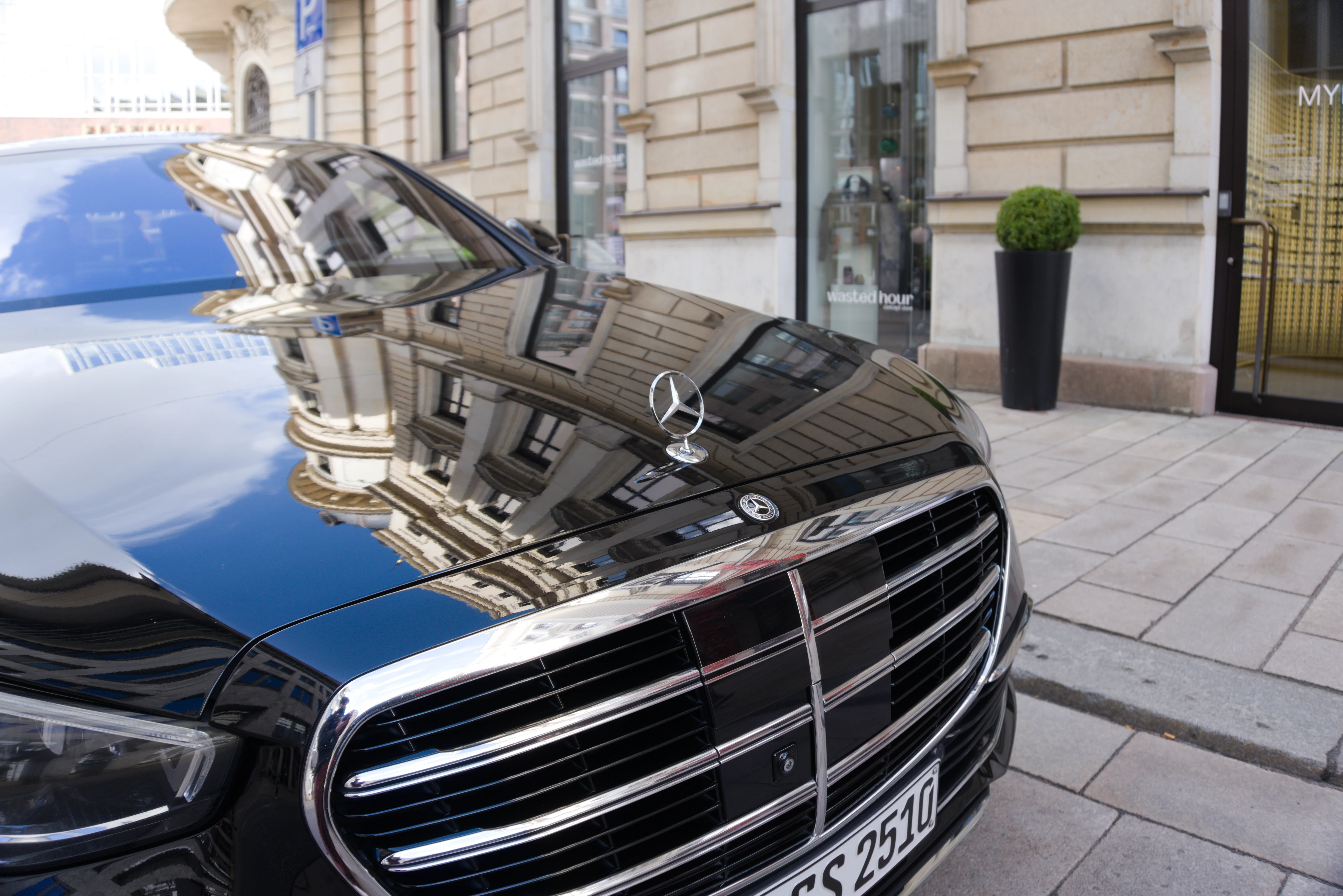 Kühlergrill einer schwarzen Mercedes-Benz S-Klasse vor einer Hausfassade