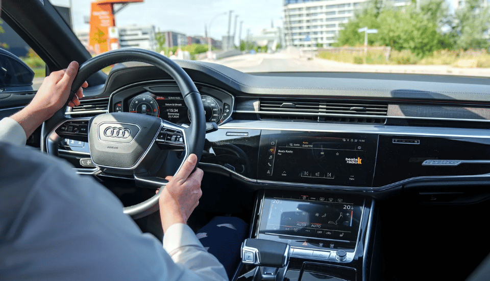 Chauffeur am Steuer eines Audi A8 während einer Stadtfahrt