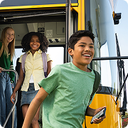 Students exiting a school bus, smiling and holding a phone, with vibrant background.