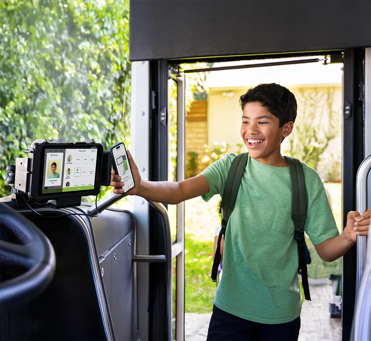 A smiling student scanning his phone on a Zum Services, Inc. bus tablet as he boards.