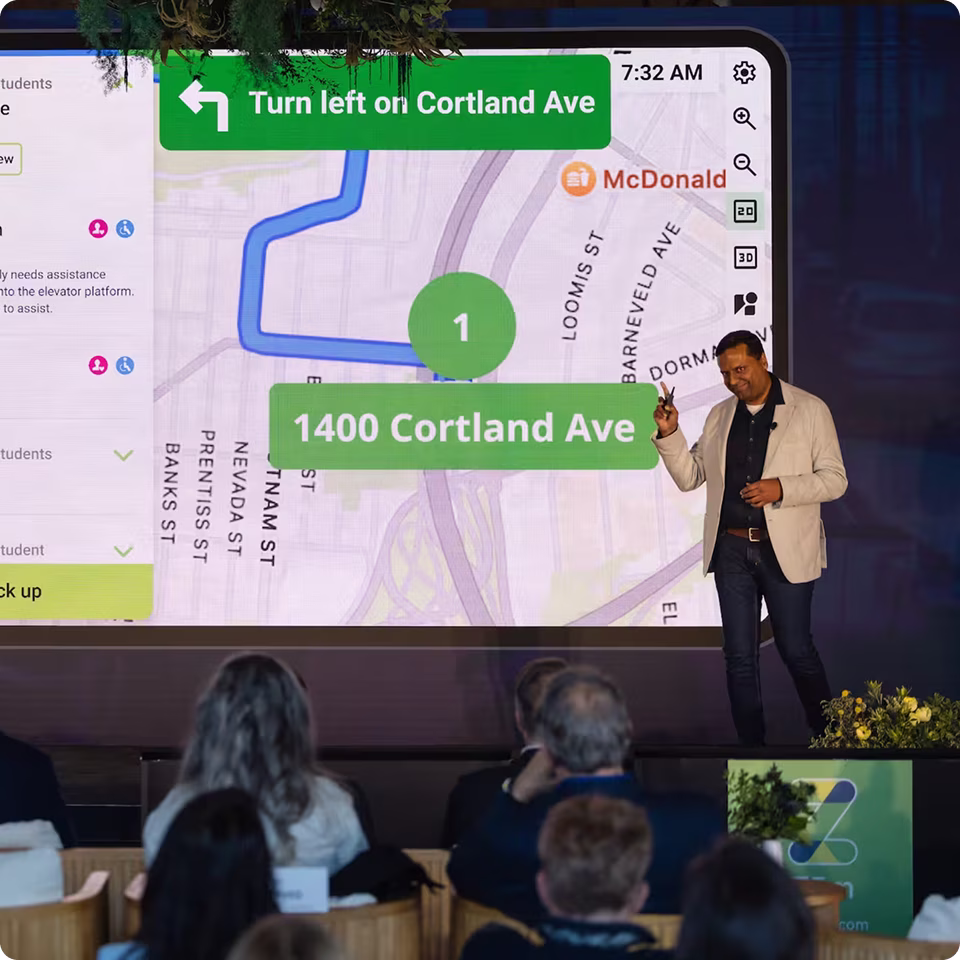 A speaker presents a navigation app interface showing directions to 1400 Cortland Ave.