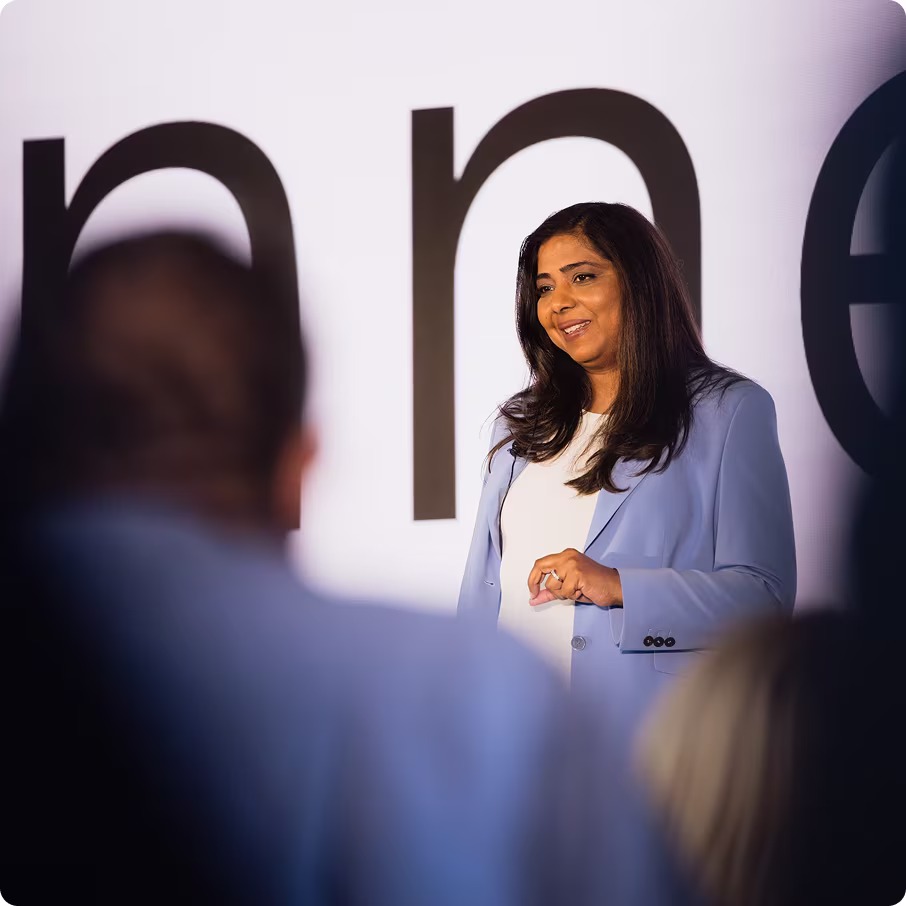 A speaker addresses an audience at a presentation, showcasing a thoughtful expression and