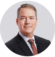 Executive portrait of a middle-aged man in a suit and tie, smiling confidently.