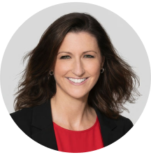 Professional woman with dark hair and a bright smile, wearing a black blazer and red top.