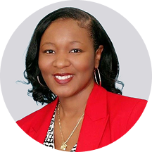Smiling woman in a red blazer with curly black hair against a light gray background.