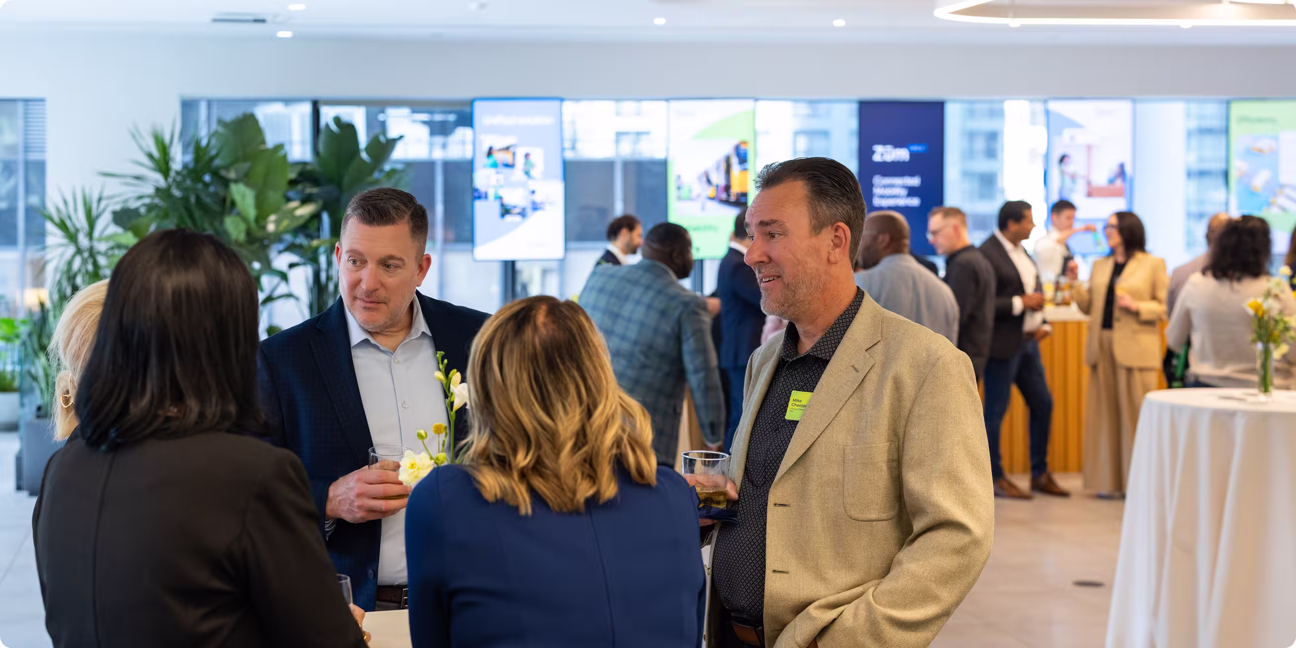 Group of professionals networking at a conference with digital displays in the background.