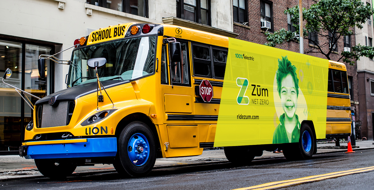 Yellow school bus with electric branding and a child's face, parked on a city street.