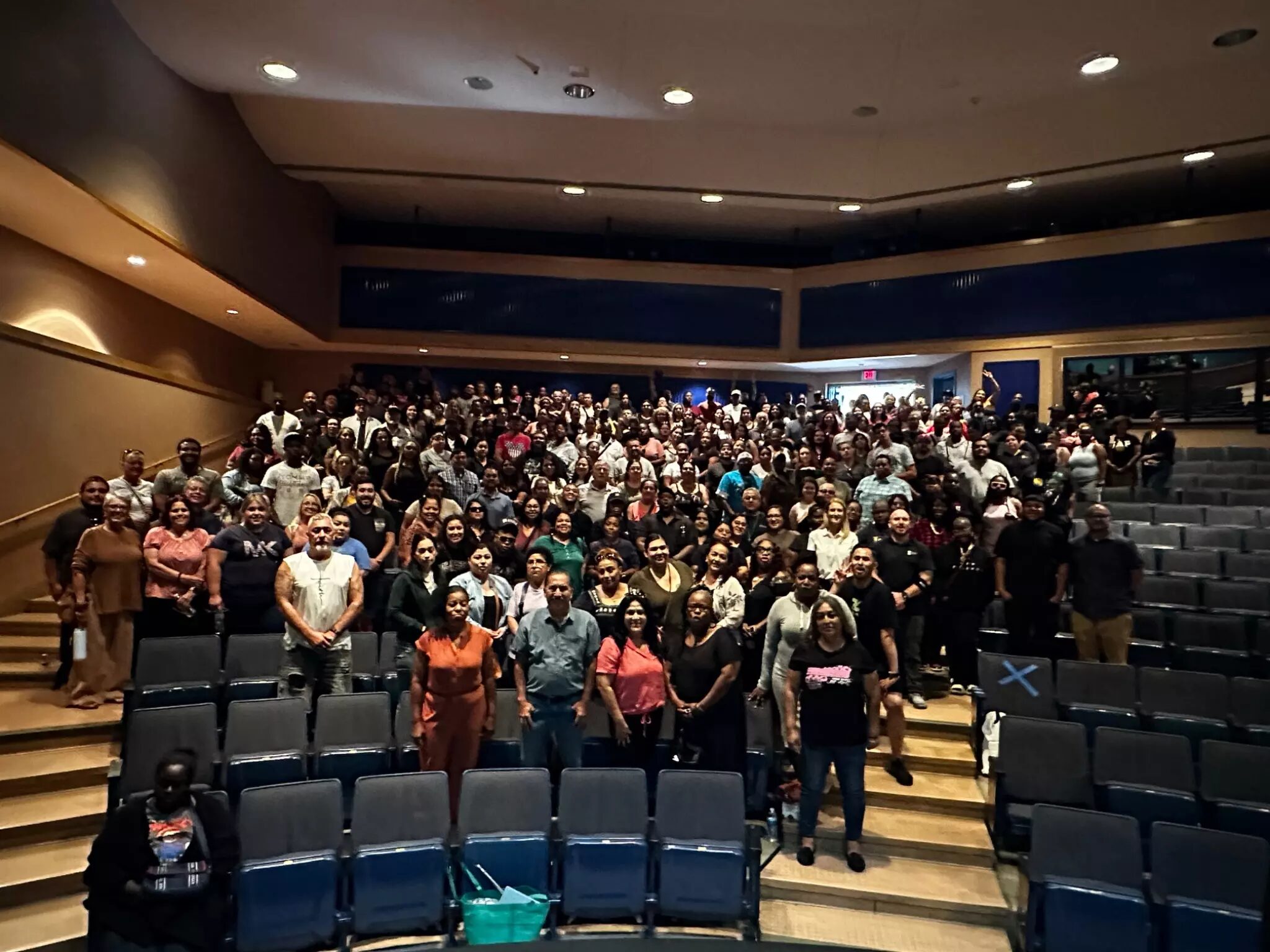 A large group of people gathered in a theater, posing for a group photo.