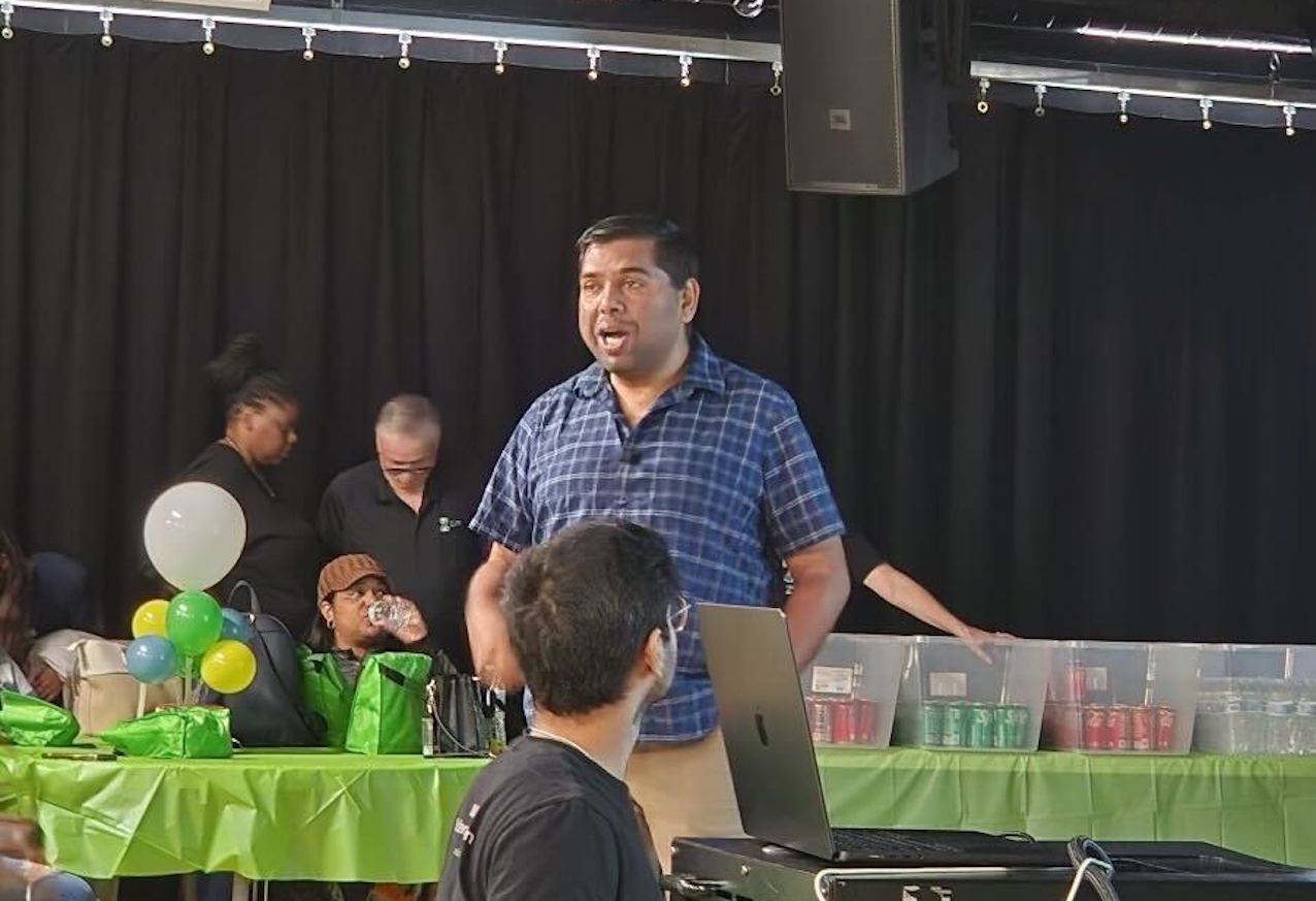 A speaker addressing an audience at a school transportation event with attendees in the background.