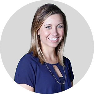 Kristen Howell smiling, wearing a navy top, against a light gray background.
