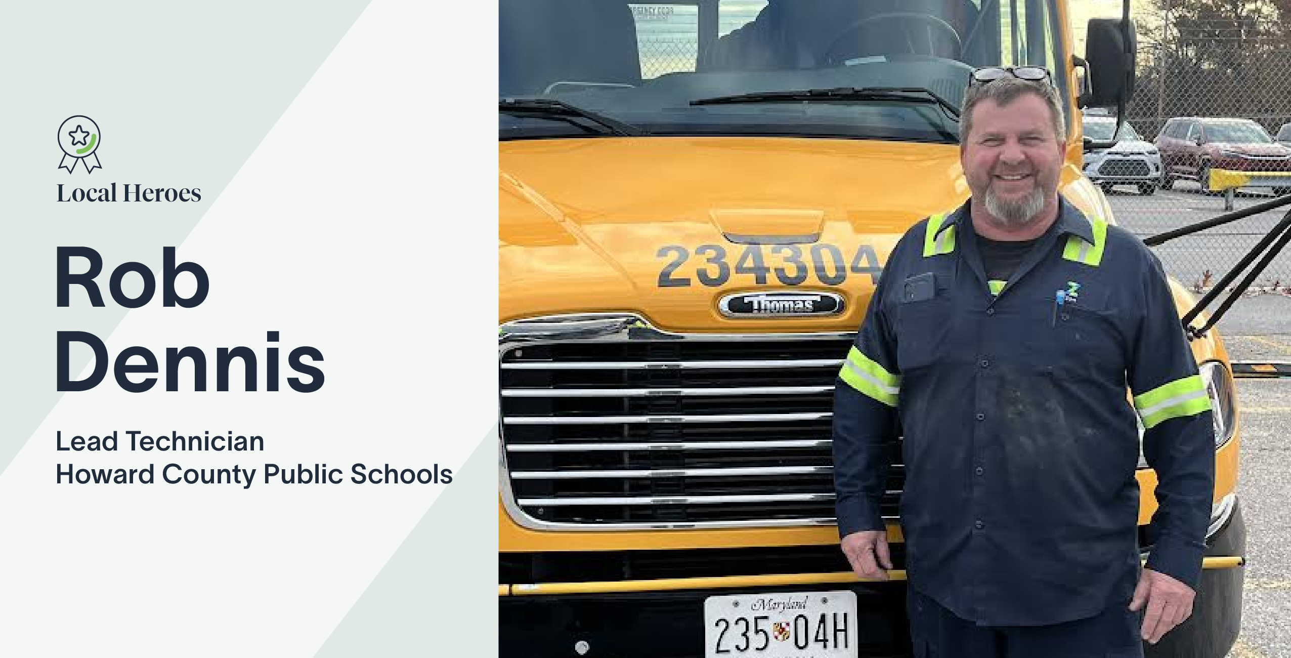 Rob Dennis stands beside a school bus, wearing a uniform and smiling at the camera.