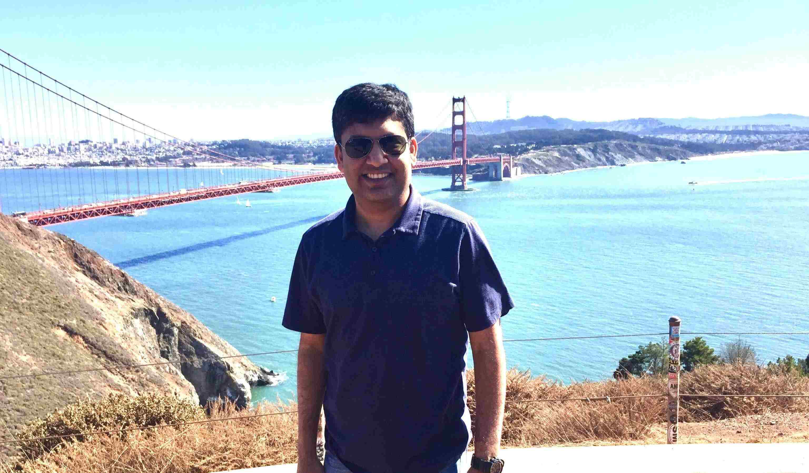 Rohit Jain stands by the Golden Gate Bridge, overlooking the bay on a sunny day.