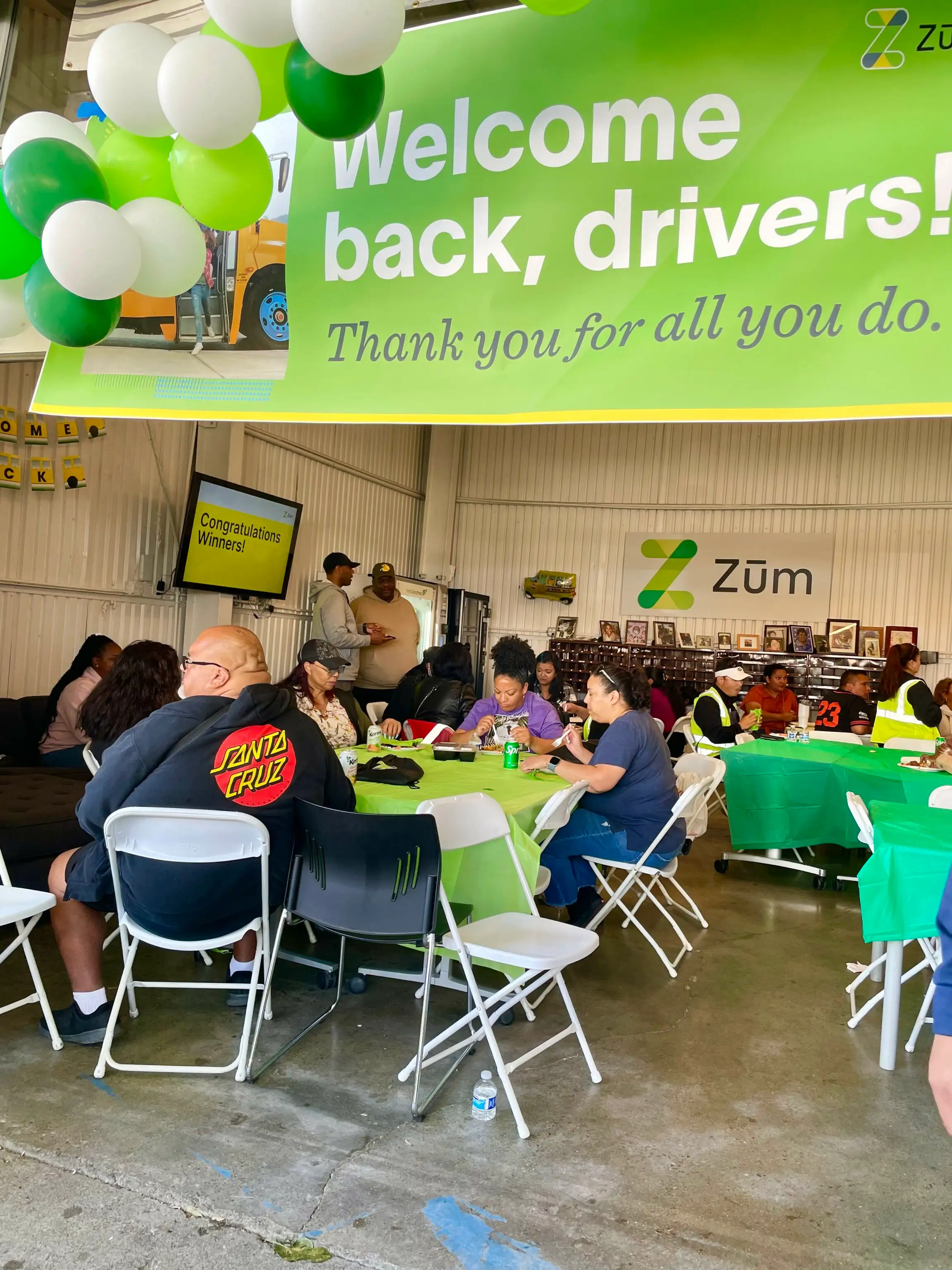 Welcome back event for Zum drivers, featuring tables with green tablecloths and balloons.