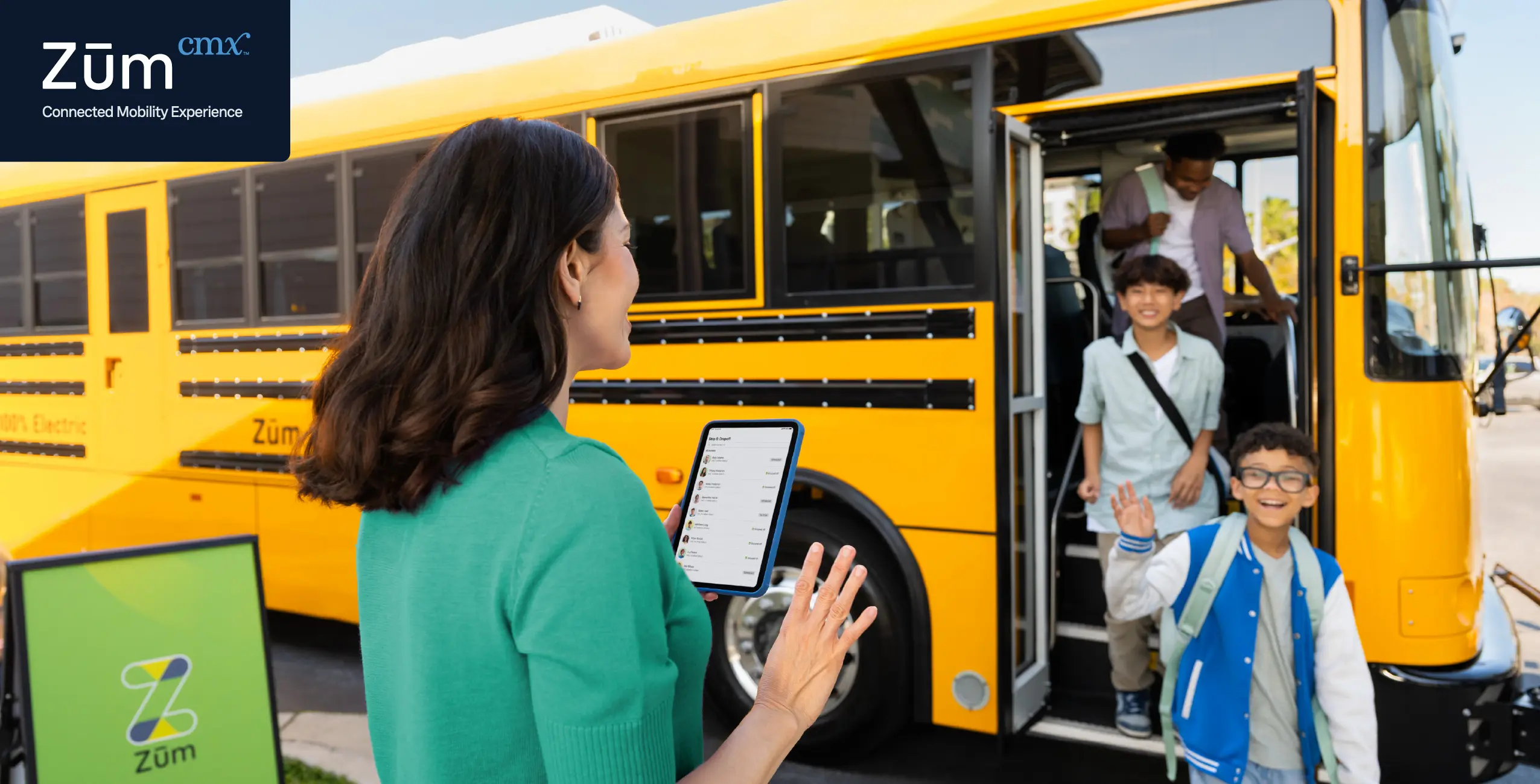 A parent greets children boarding a yellow school bus, with a tablet in hand and Zum branding