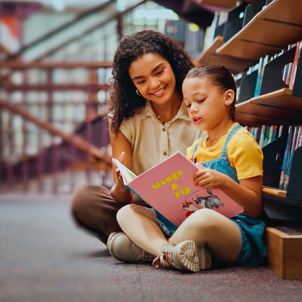 A parent and child reading a book together in a school library, featured in a Zum Services, Inc. case study.