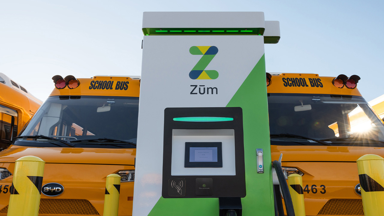 Zum EV charger in front of yellow school buses, supporting electric school transportation.