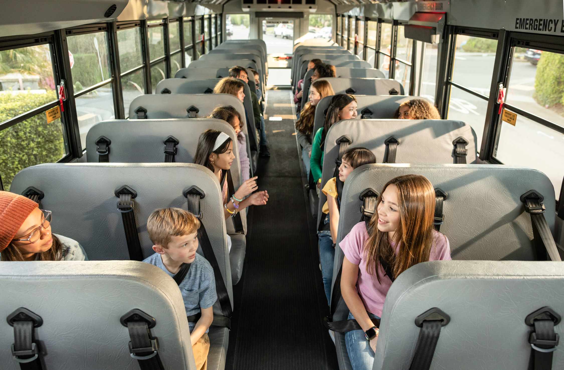 Students seated on a school bus, engaging in conversation during a trip.