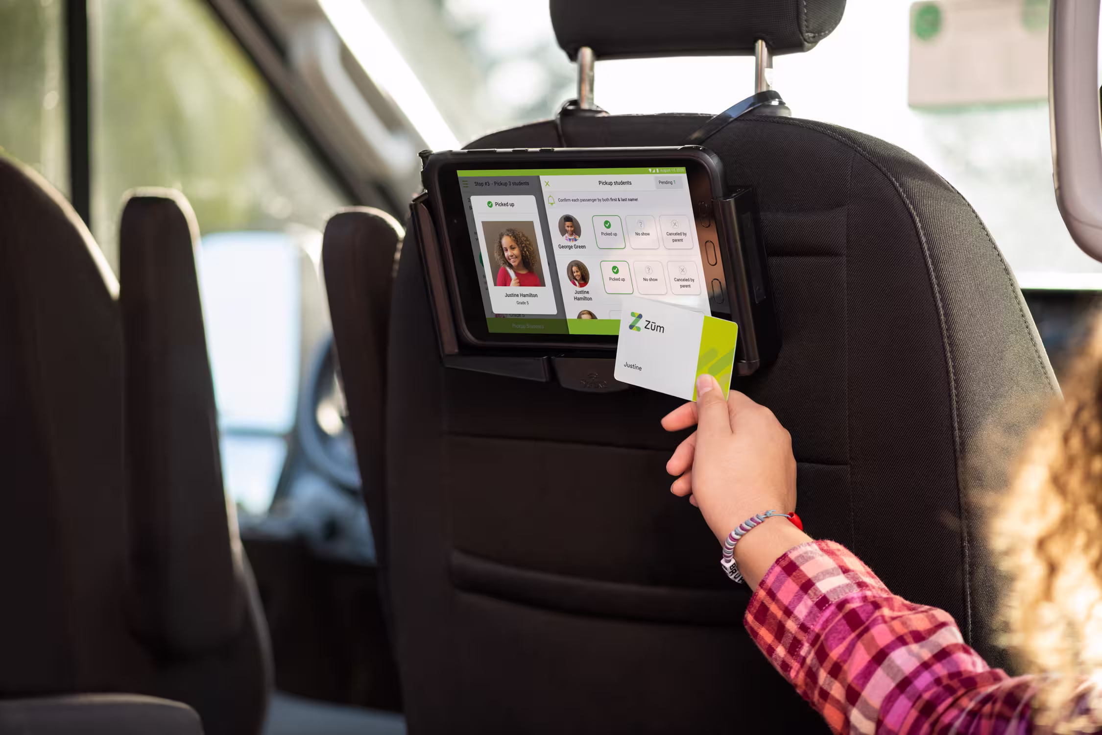 Tablet mounted on a bus seat shows driver app with user profiles and a Zum. card being scanned.