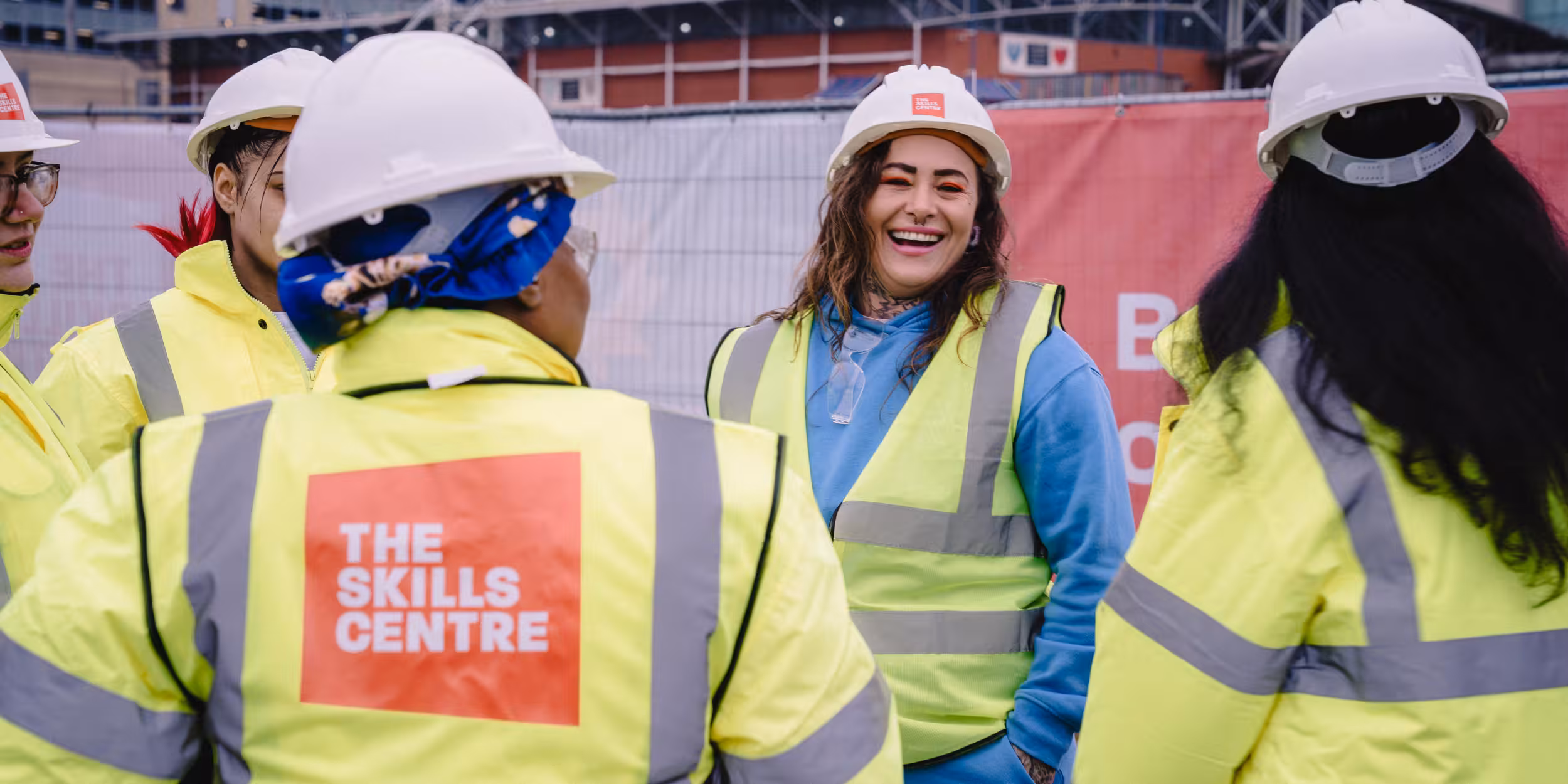 People gathered talking and laughing wearing hard hats and hi vis