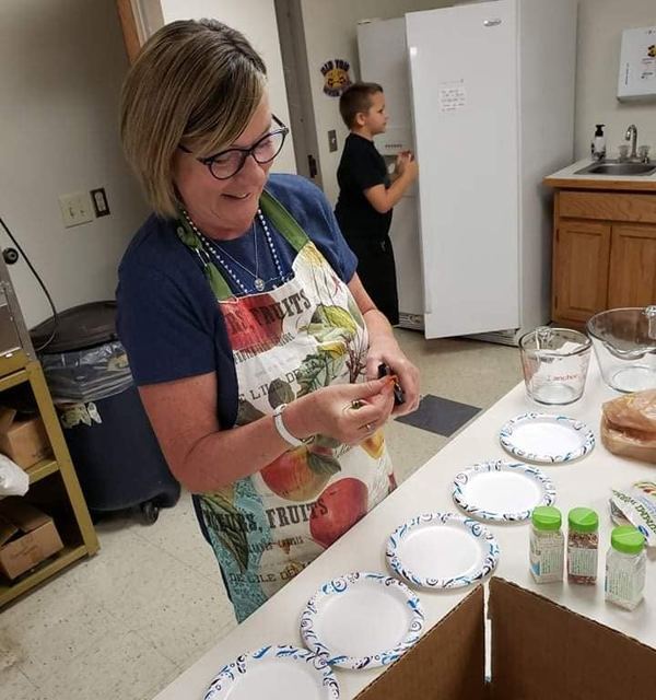 A woman in an apron smiles while she works in the kitchen at Faith Lutheran Church in Derby, Kansas. 