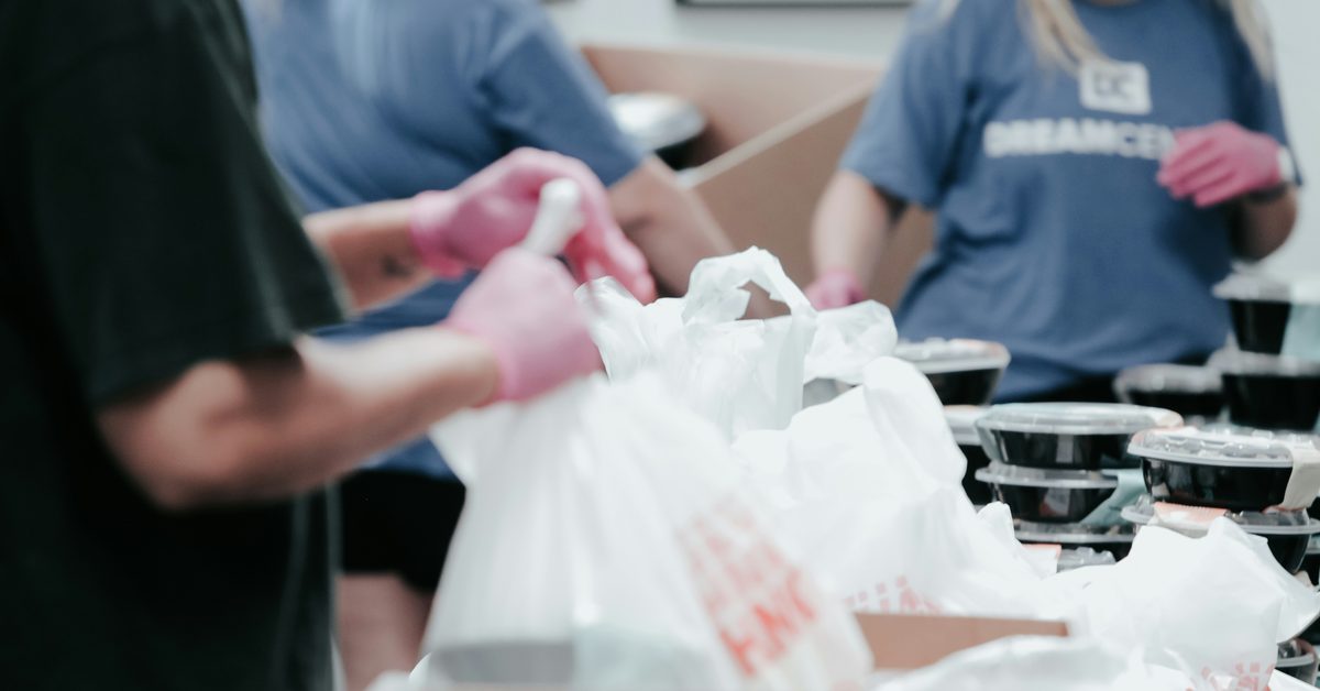 A stock photo of volunteers handling plastic grocery bags.