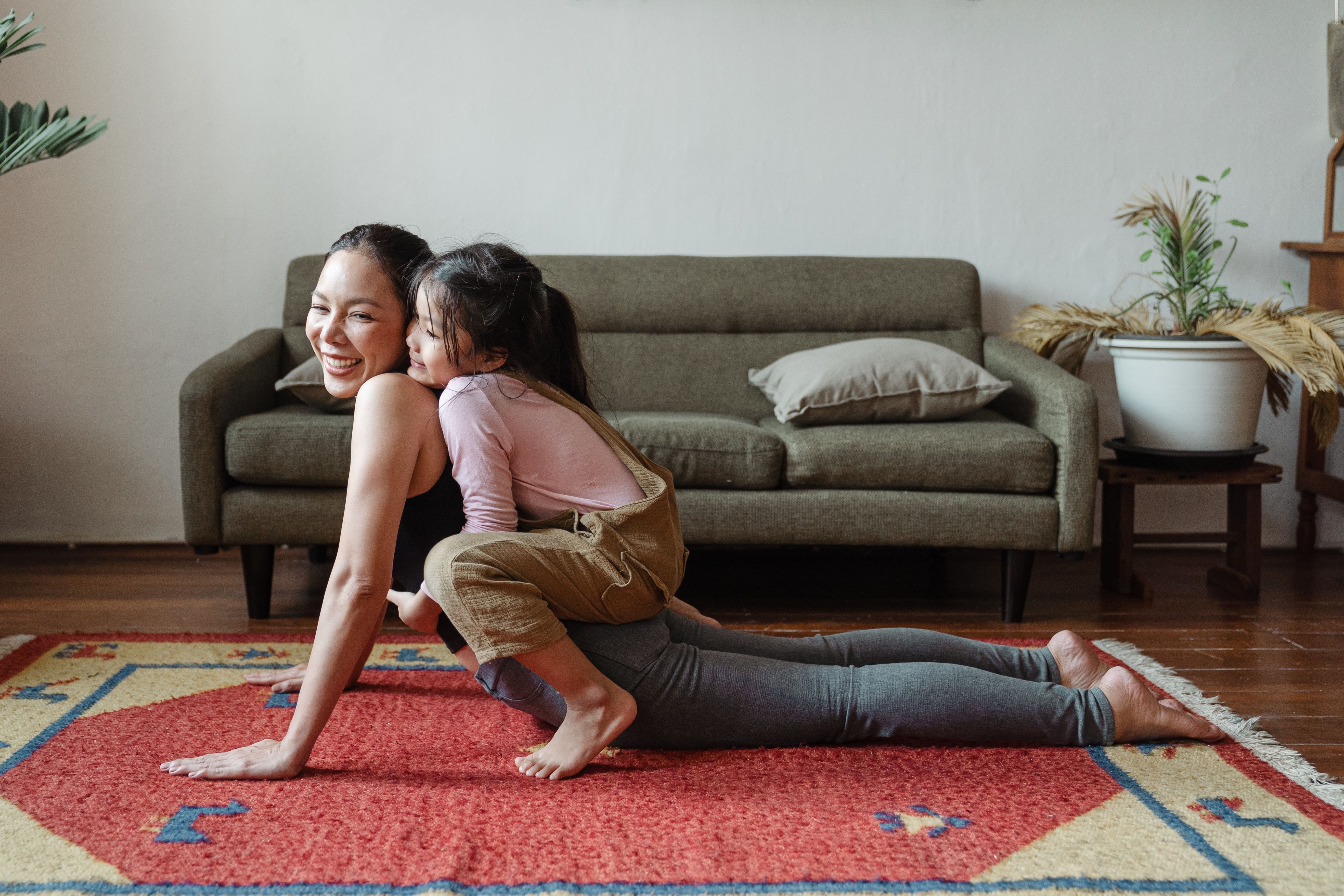 Woman and child exercising together on living room floor with potted plants