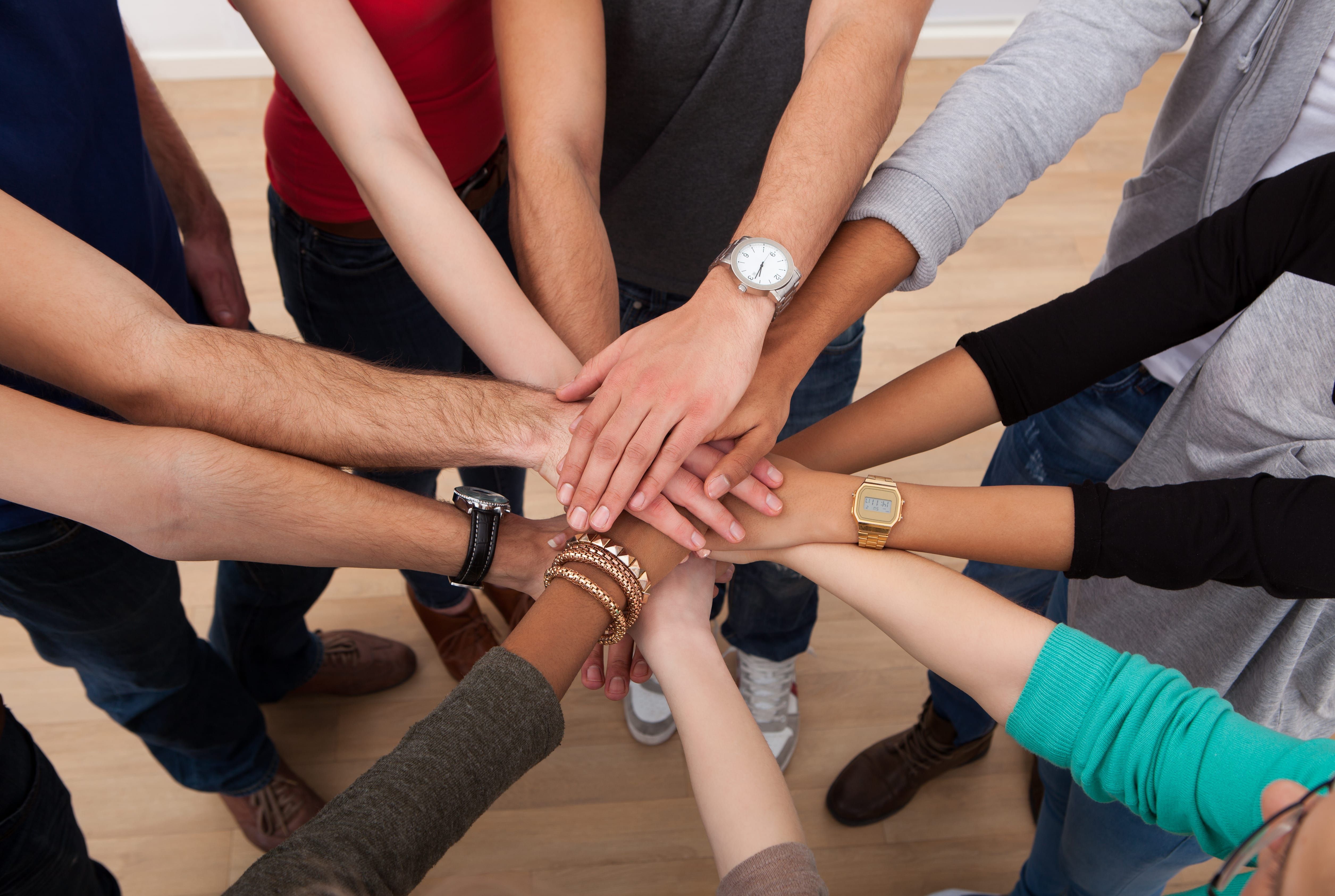 Group of diverse people joining hands together in unity and teamwork gesture