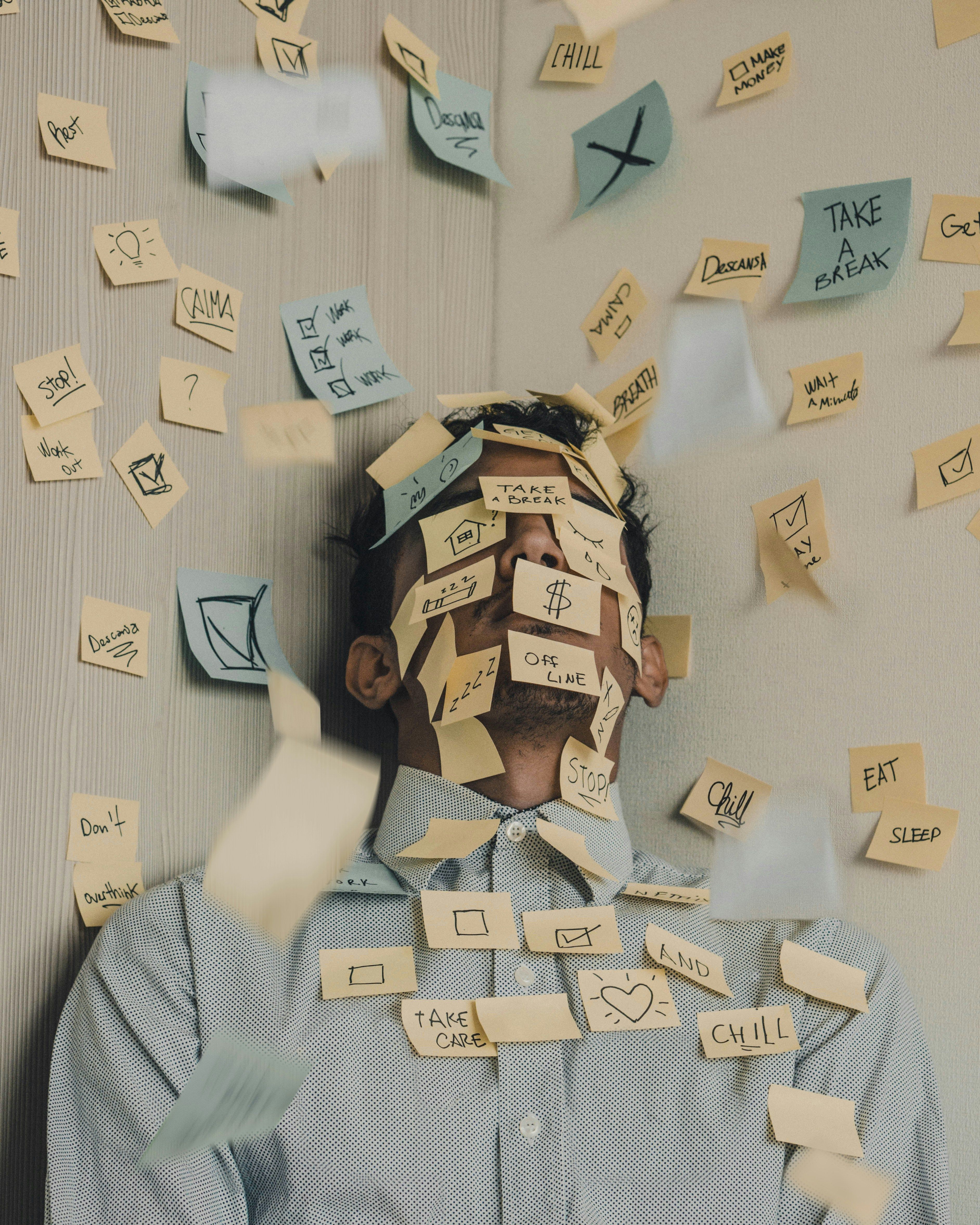 Person covered with sticky notes showing thoughts and reminders like work, chill, and take care.