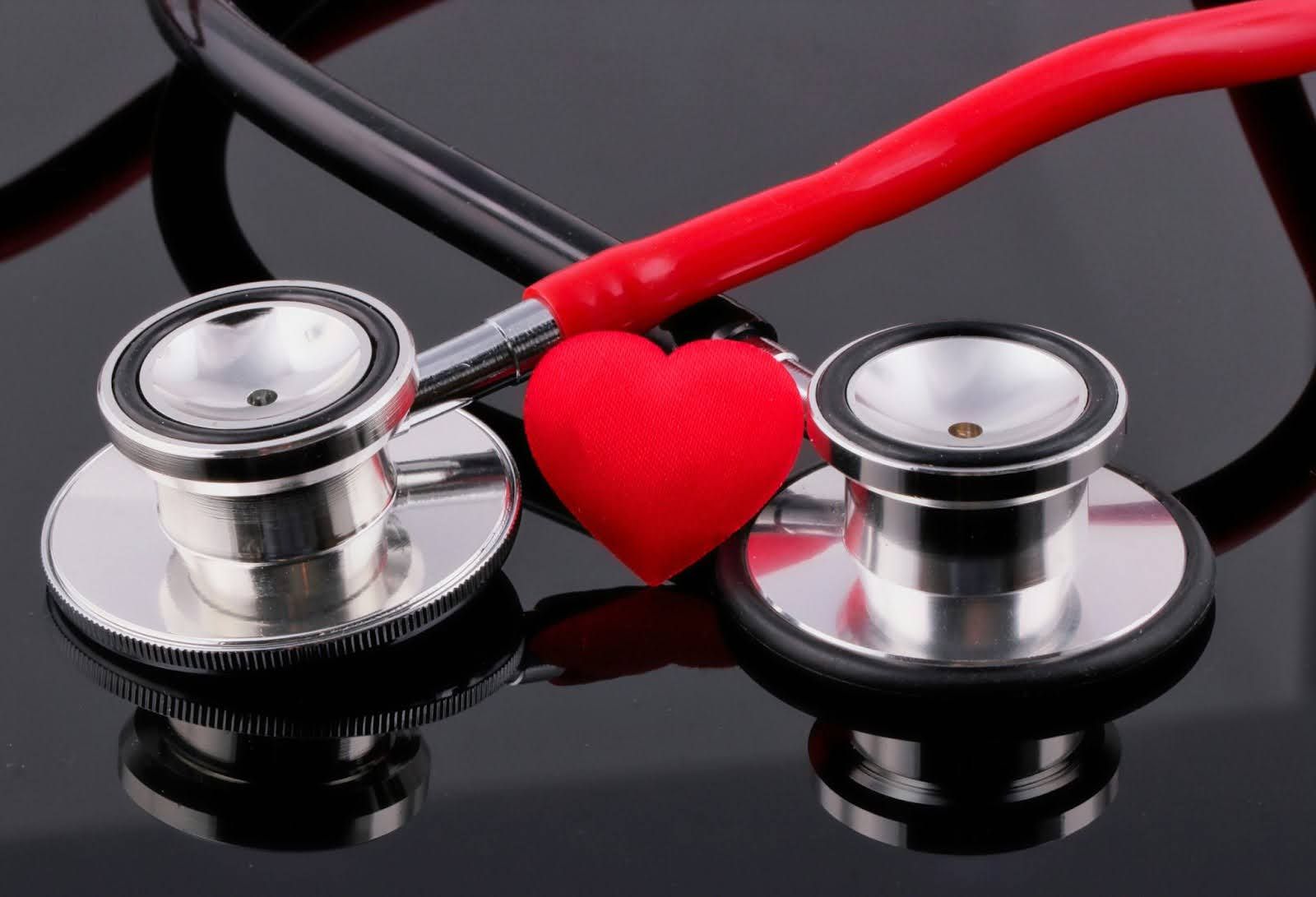 Red stethoscope with small red heart between two metal earpieces on gray background