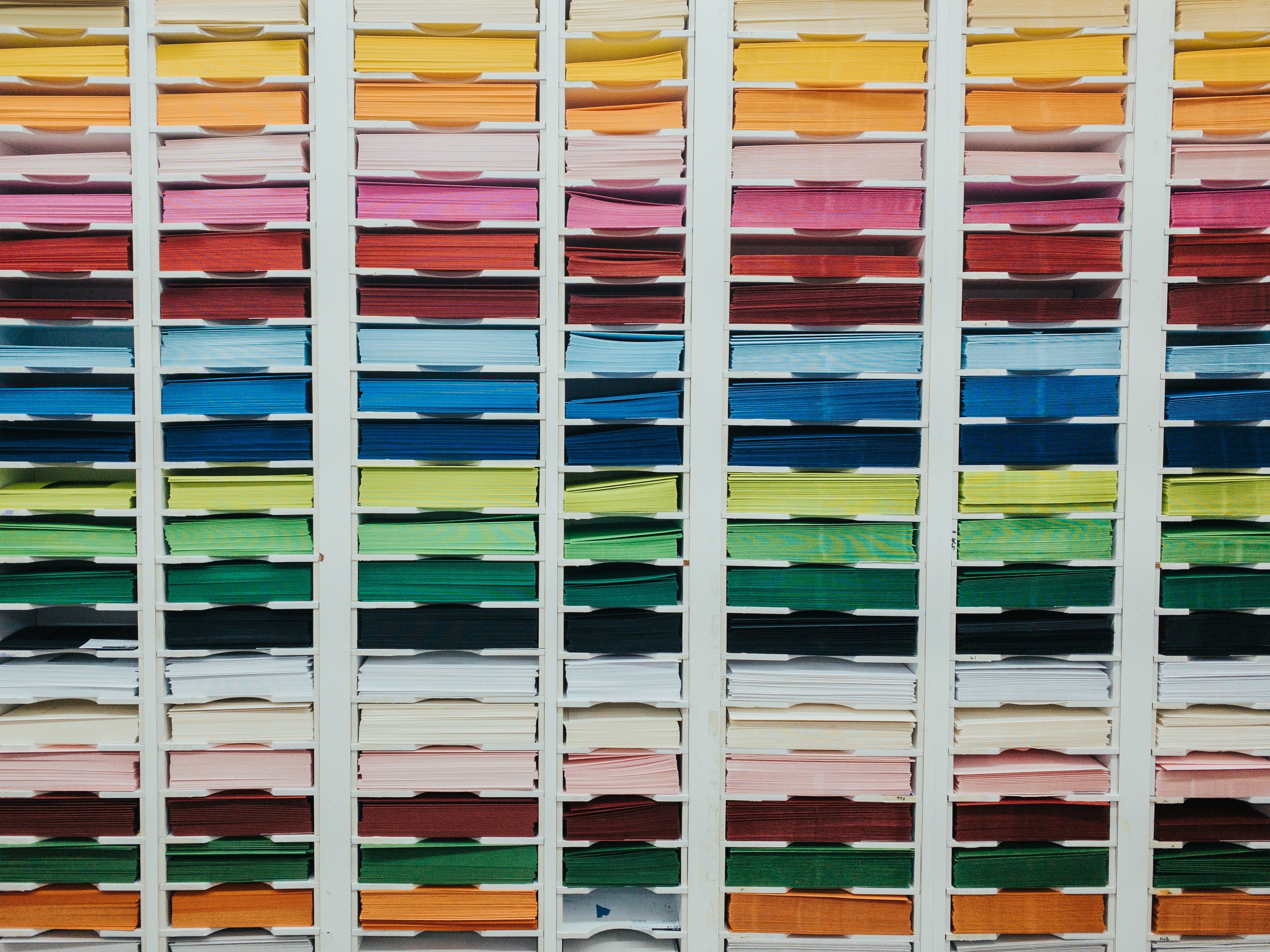 Organized color storage shelves with stacked fabric or material samples in rainbow hues