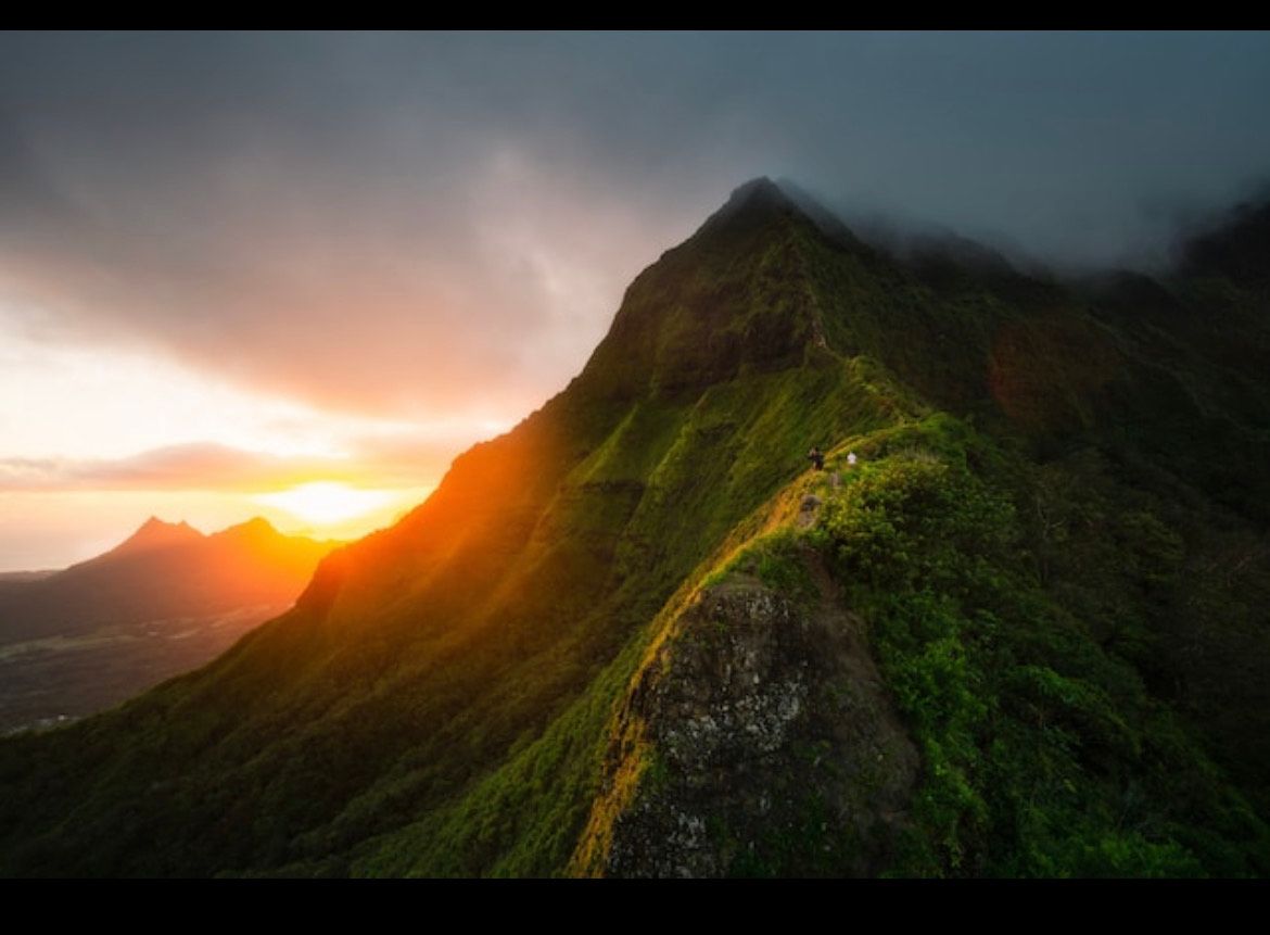 Moss-covered mountain ridge at sunset with golden light illuminating volcanic peaks