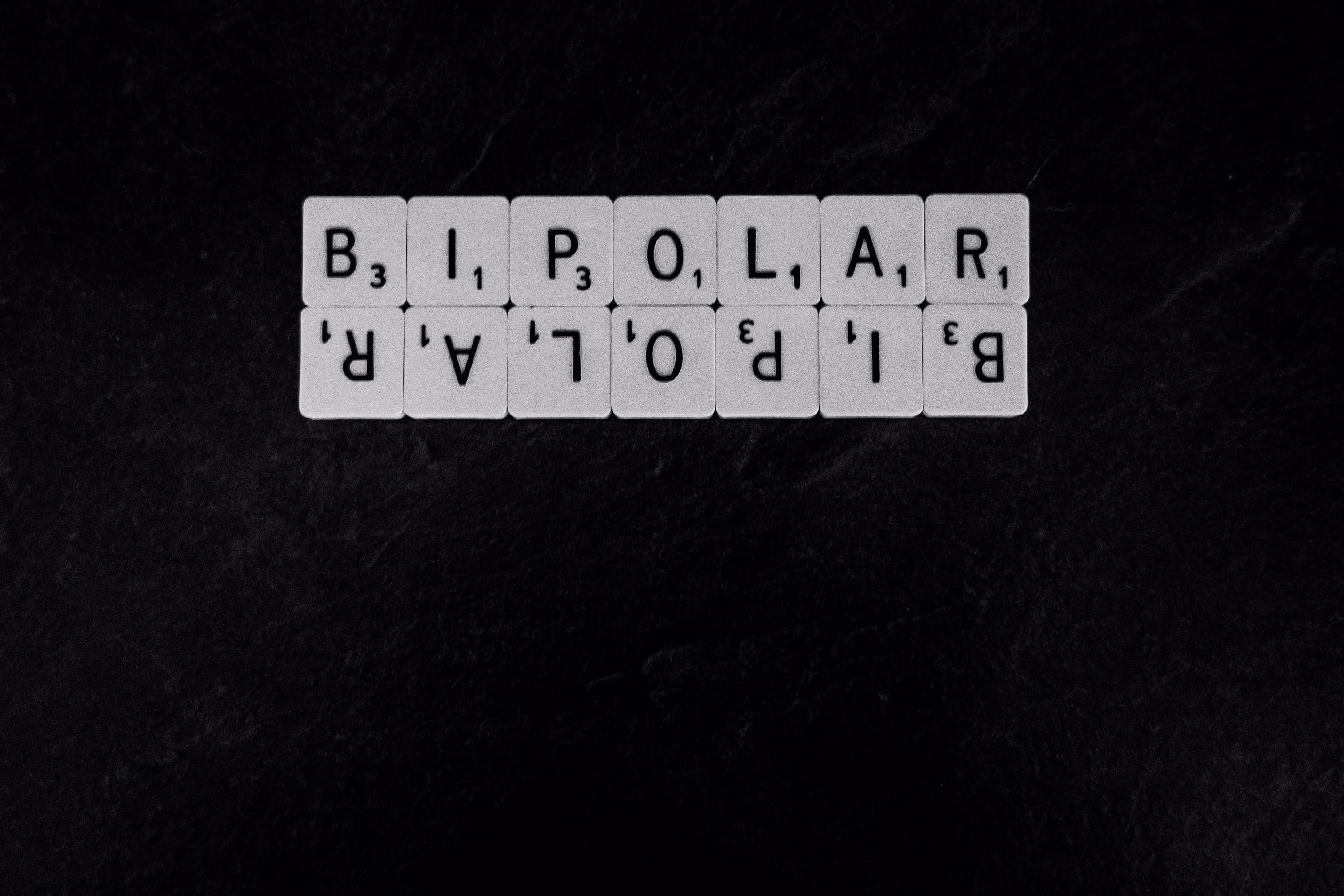 Scrabble tiles spelling BIPOLAR with point values on dark background