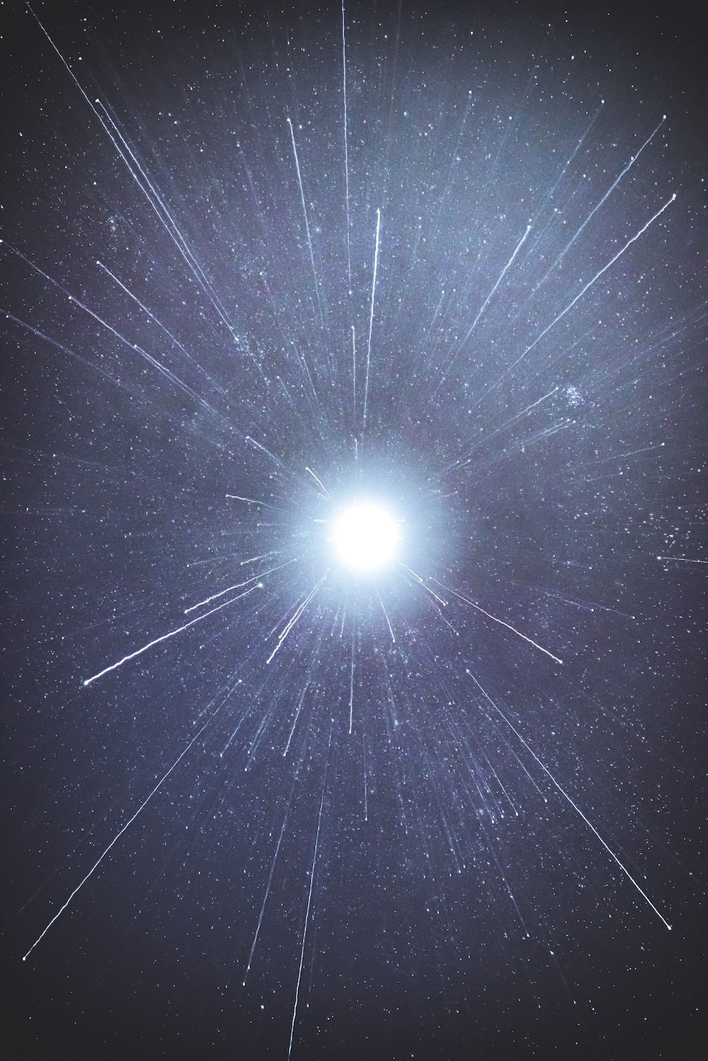 Bright star with radiating light rays and particles against starry night sky