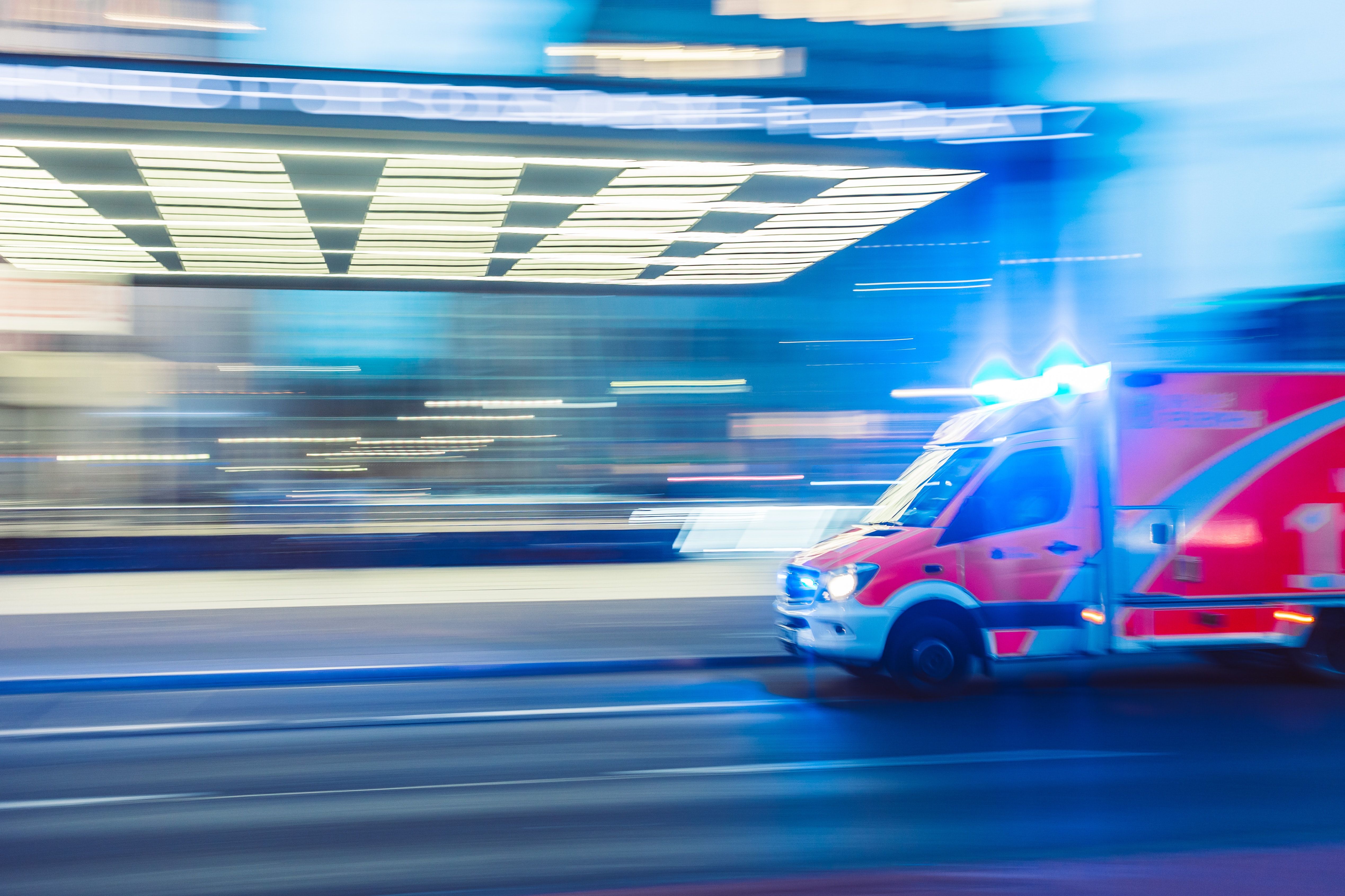 Emergency ambulance with lights on, fast moving through modern hospital corridor