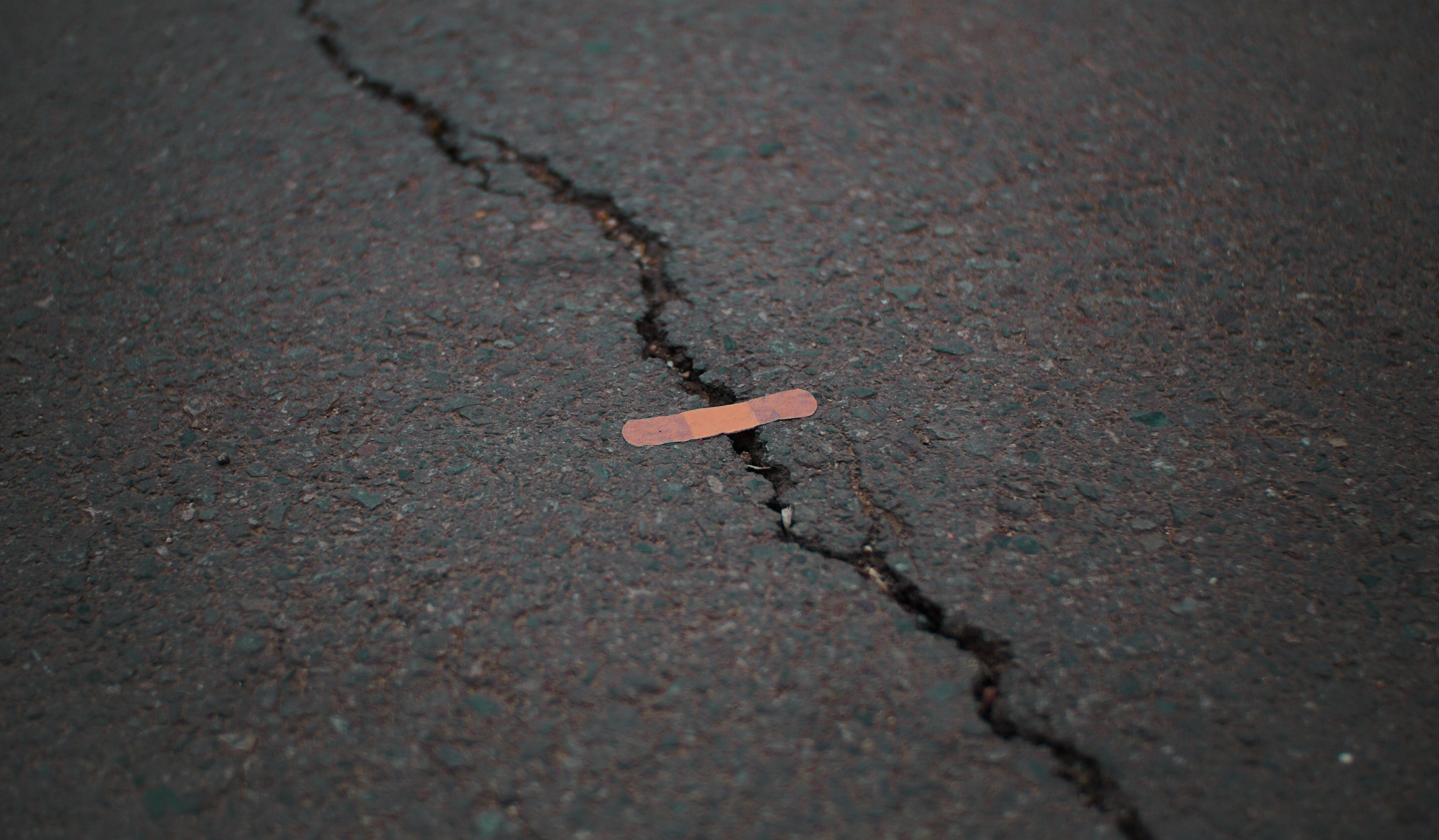 Band-aid placed on cracked asphalt pavement surface.