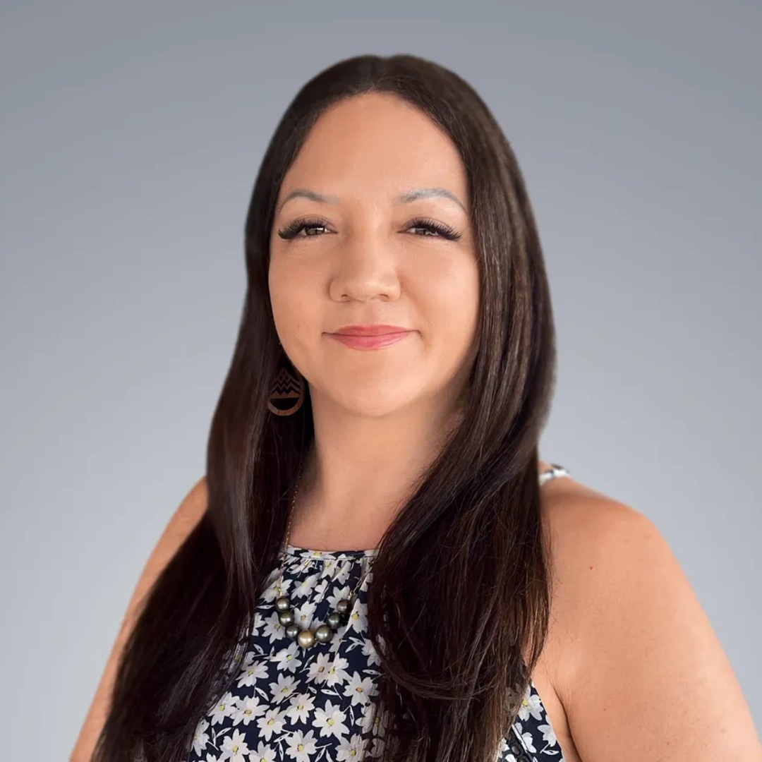 Woman with long dark hair wearing floral dress and hoop earrings