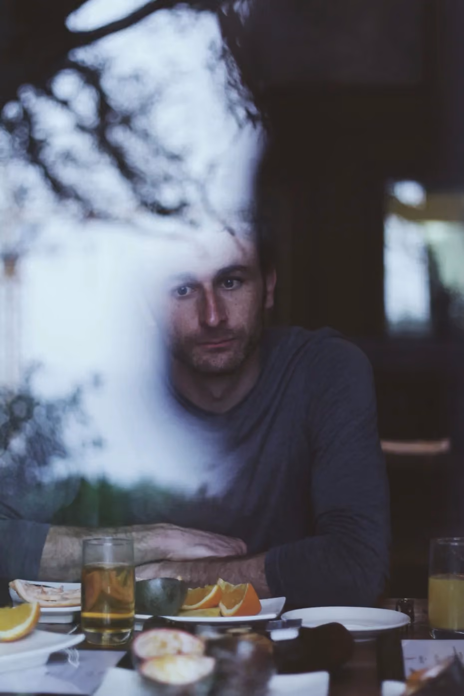 Man sitting at table with drinks and citrus fruit, white sculptural form above head