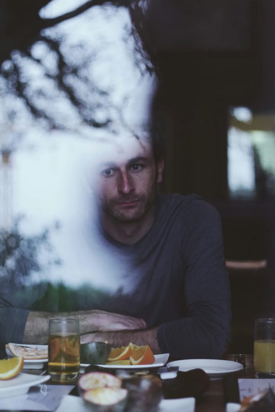 Man sitting at table with drinks and citrus fruit, white sculptural form above head