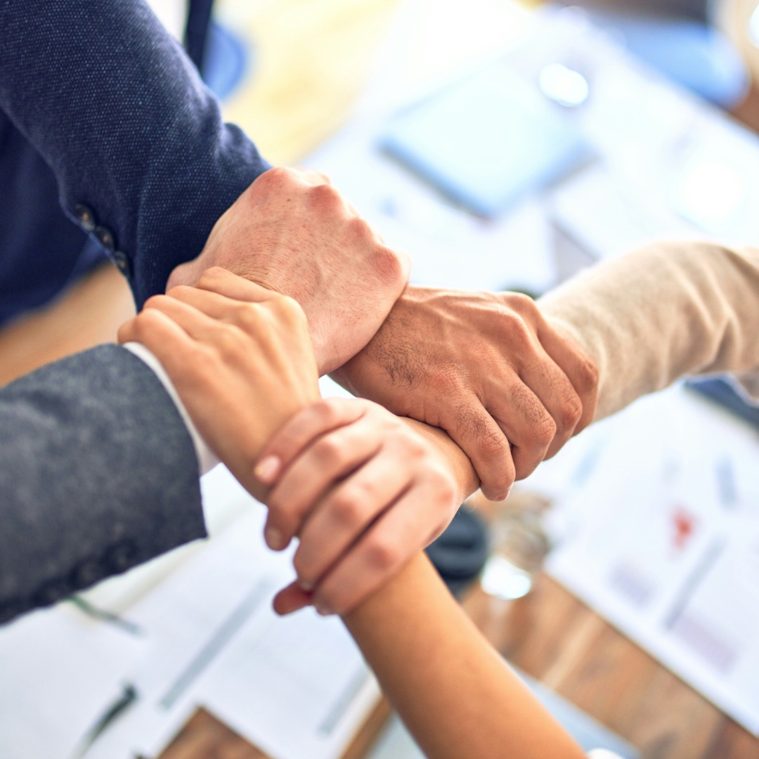 Team of business professionals stacking hands together in unity and solidarity