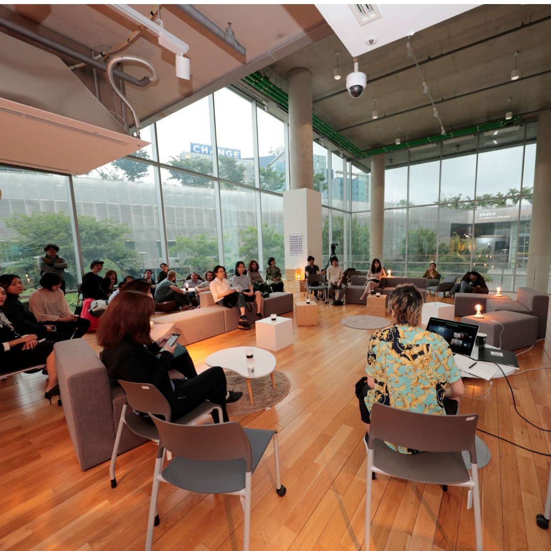 Large group of people seated in modern office lounge with floor-to-ceiling windows overlooking city