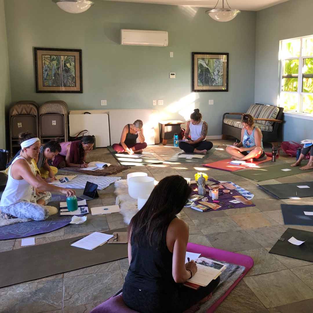 Group of women practicing yoga on mats in a bright, green-walled studio room