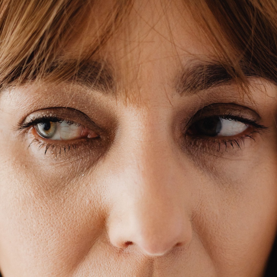 Close-up portrait of a person's face looking downward with brown hair and amber eyes.