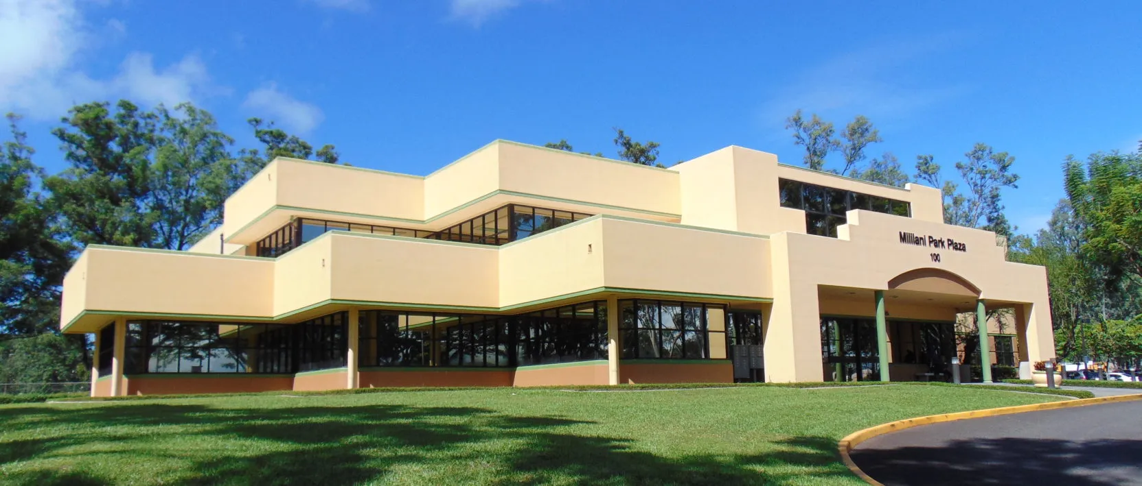 Modern cream-colored building with green trim and arched entrance labeled Milliani Park Plaza