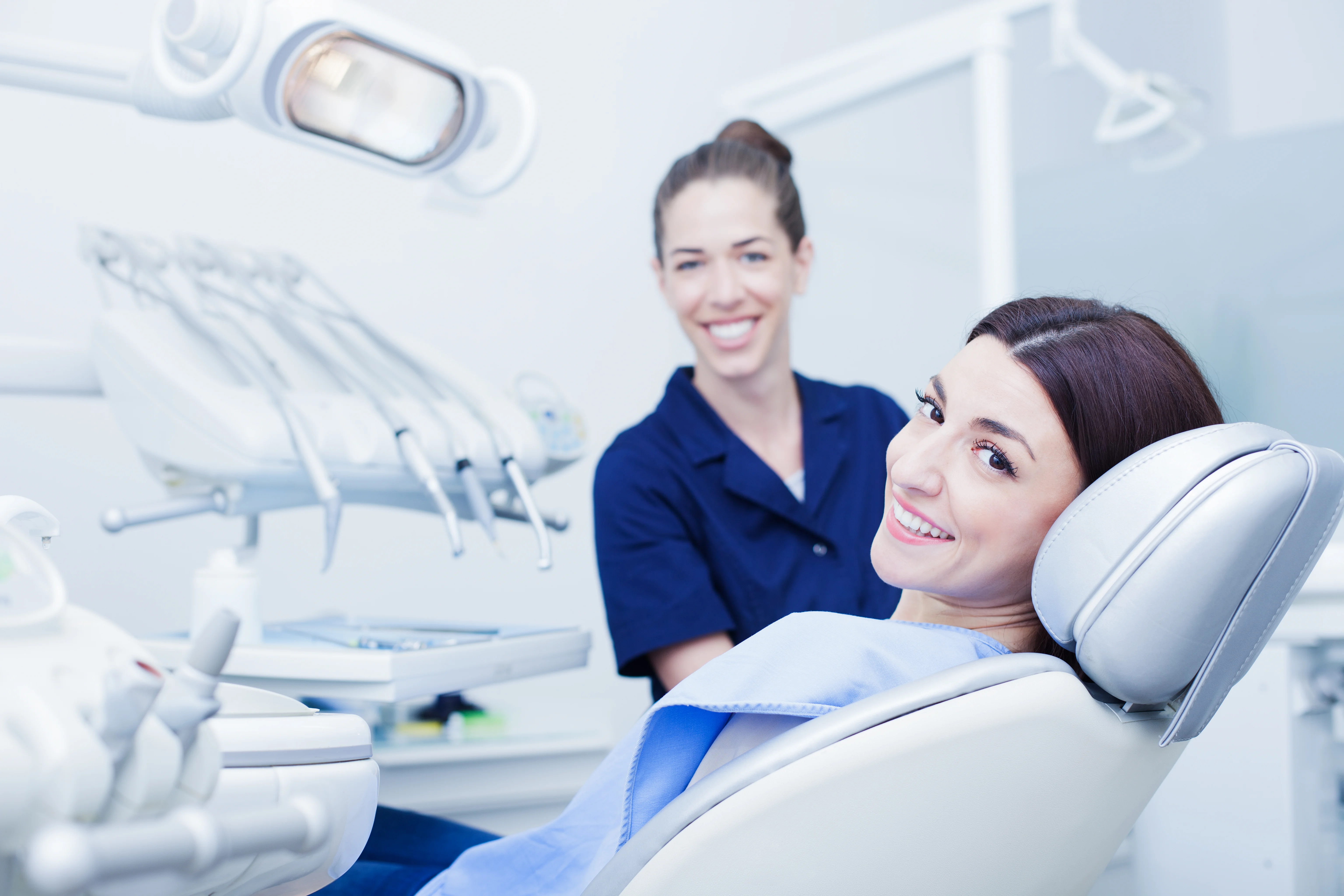 Smiling patient in a dental chair with a dental nurse standing behind her