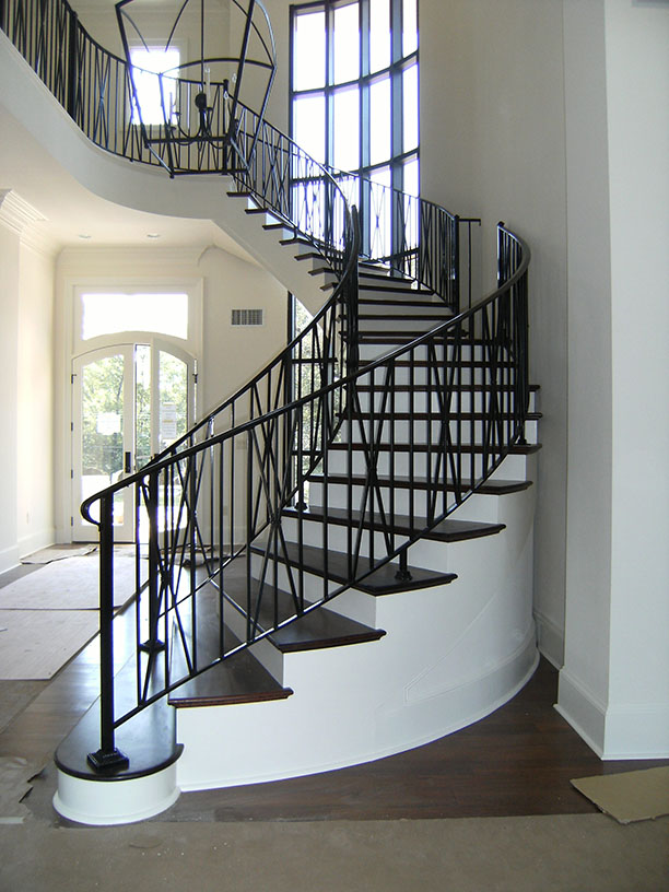 Curved staircase with dark wood steps and black metal railings in a bright modern entryway.